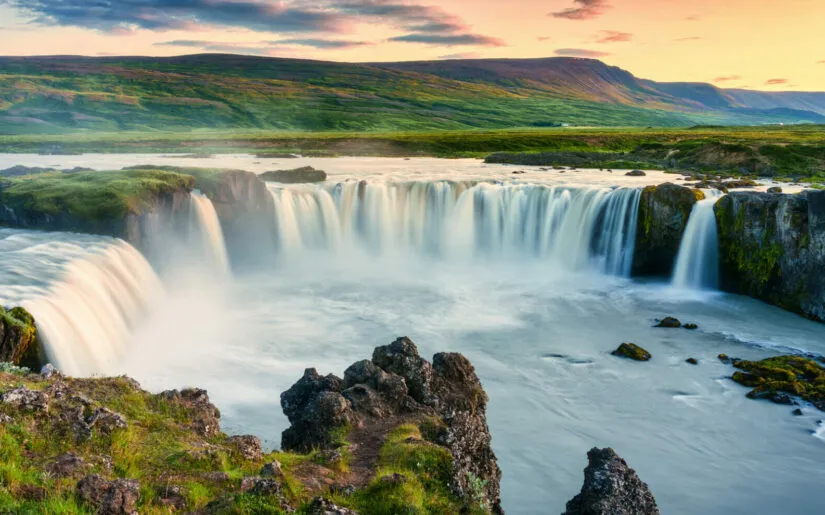 Majestic landscape of Godafoss waterfall or waterfall of the gods flowing and colorful sunset sky on Skjalfandafljot river in summer at Northern Iceland