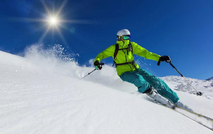 Skifahrer, der abwärts im Hochgebirge Ski fährt