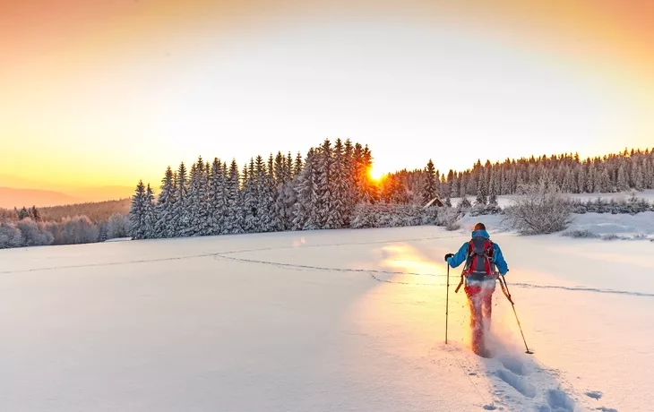 Sonnige Winterlandschaft mit Mann auf Schneeschuhen.