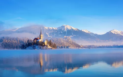 Bleder See an einem sonnigen Wintermorgen mit klarem Himmel und schneebedeckten Bergen