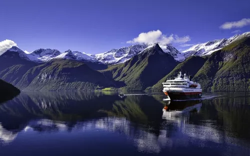 Kreuzfahrtschiff im Hjørundfjord in Norwegen vor schneebedeckten Bergen.