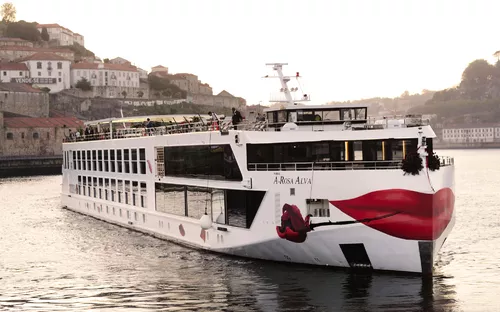 Schiff auf einem Fluss mit bemaltem Bug vor einer Stadt im Hintergrund.