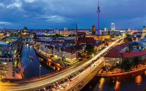 Blick auf das nächtliche Berlin mit Fernsehturm und beleuchteten Straßen.