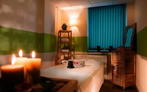 Entspannungsraum mit Massagebett, Kerzen und Regalen im AHORN Waldhotel Altenberg.