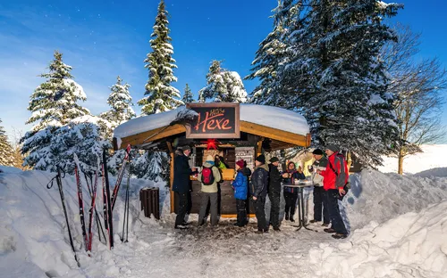 Menschen vor einer verschneiten Waldhütte mit dem Schild 