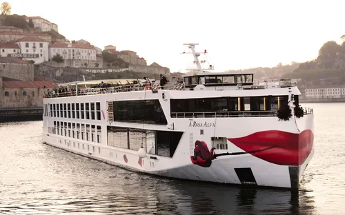 Schiff auf einem Fluss mit bemaltem Bug vor einer Stadt im Hintergrund.