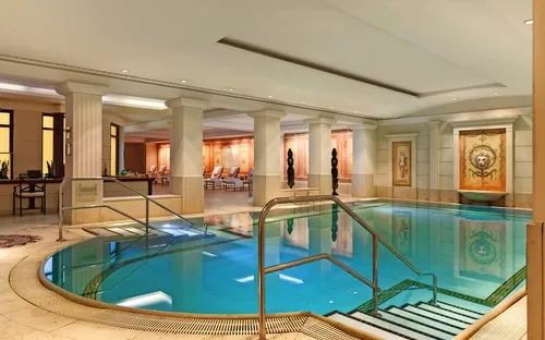 Luxuriöser Innenpool mit Liegestühlen und beigen Wänden in einem eleganten Raum.