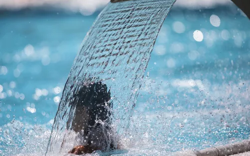 Wasserfall im Spa-Bereich eines Schwimmbads mit sprudelndem Wasser und entspannender Atmosphäre.