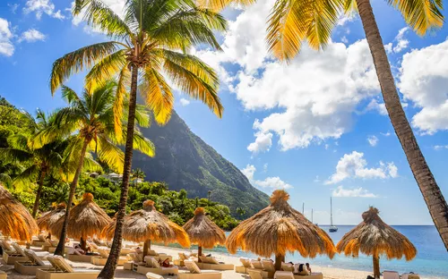 Strand mit Palmen und Strohhütten vor dem Berg Gros Piton auf St. Lucia, Karibik.