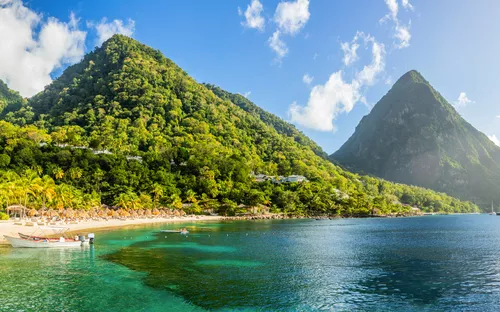 Strand und Meer vor tropischen Bergen unter blauem Himmel