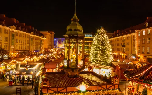 Weihnachtsmarkt bei Nacht mit beleuchtetem Weihnachtsbaum und Verkaufsständen