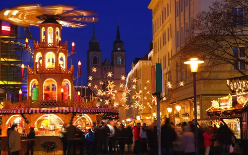 Weihnachtsmarkt mit beleuchteten Ständen und Besuchern in der Dämmerung.