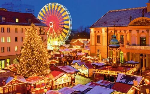 Weihnachtsmarkt mit beleuchtetem Riesenrad und geschmücktem Weihnachtsbaum bei Abenddämmerung