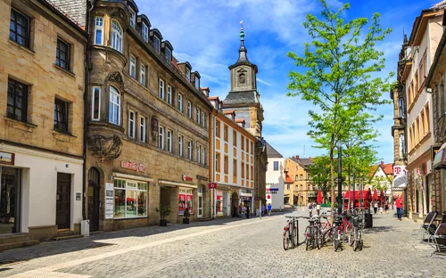 Straßenansicht mit historischen Gebäuden und Fahrrädern, klarer Himmel im Hintergrund.