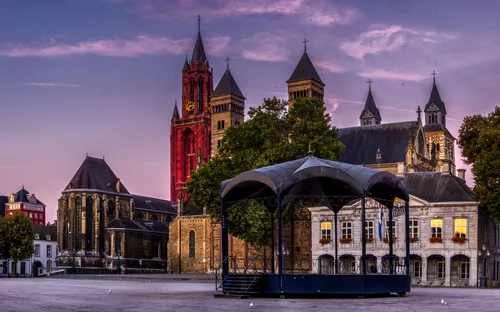 Panoramablick auf den Vrijthof Platz in Maastricht, Niederlande, mit historischen Gebäuden und einem Pavillon im Vordergrund bei Sonnenuntergang.