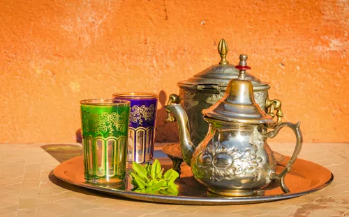 Silberne Teekanne und zwei bunt verzierte Teegläser auf einem Tablett.