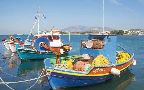 Zwei bunte Fischerboote im Hafen vor Berglandschaft.