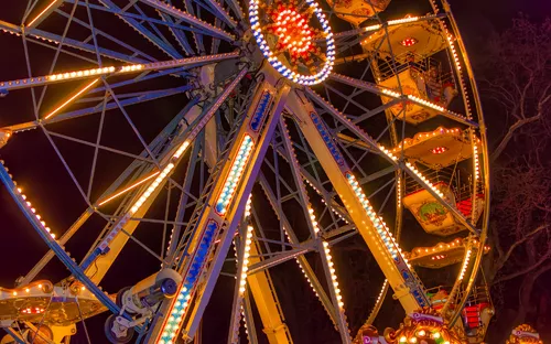 Riesenrad bei Nacht mit Beleuchtung vor dunkelrotem Himmel.