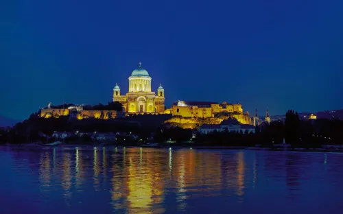 Erleuchtete Basilika Esztergom bei Nacht, reflektiert im Wasser.