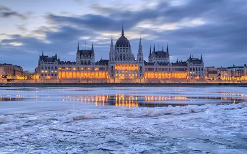 Parlamentsgebäude in Budapest bei Abenddämmerung mit gefrorenem Fluss.