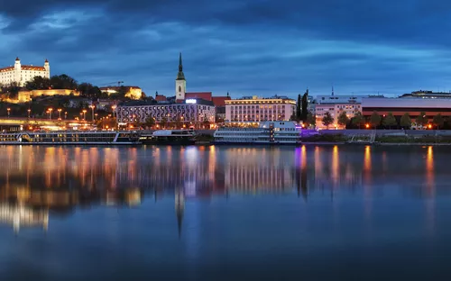 Panorama von Bratislava mit Burg und Donau bei Abenddämmerung.