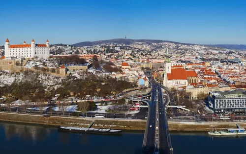 Stadtpanorama mit Burg und Fluss im Vordergrund.