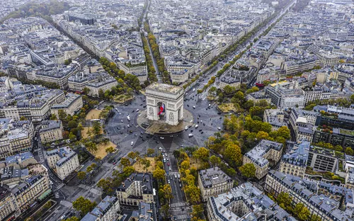 Luftaufnahme des Arc de Triomphe in Paris, umgeben von Straßen und Gebäuden.