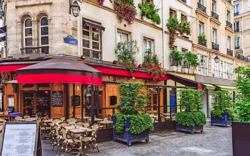 Gemütliches Straßencafé mit Außenterrasse und bepflanzten Fensterkästen.