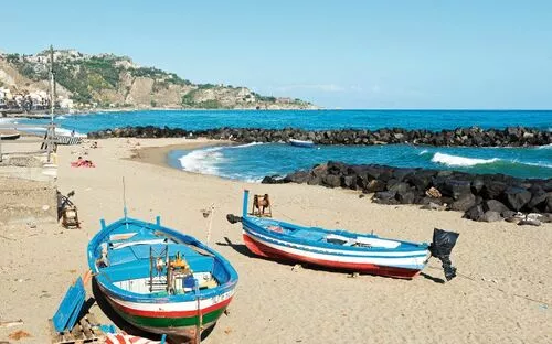 Fischerboote am sandigen Strand von Giardini Naxos, Meer und Felsenküste im Hintergrund