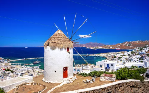 Traditionelle weiß gestrichene Windmühle mit Strohdach vor Küstenlandschaft auf Insel