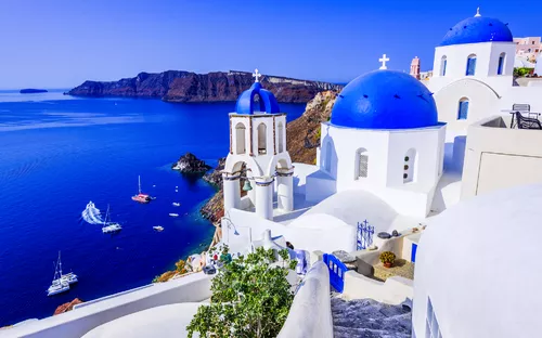 Weiße Gebäude mit blauen Kuppeln und Meerblick auf Santorin, Griechenland.