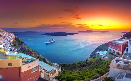 Panoramablick auf Santorin bei Sonnenuntergang mit Blick auf das Meer und ein Kreuzfahrtschiff.