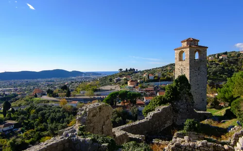 Ruinen eines alten Steinbauwerks mit Blick auf eine Landschaft und ein Dorf im Hintergrund.