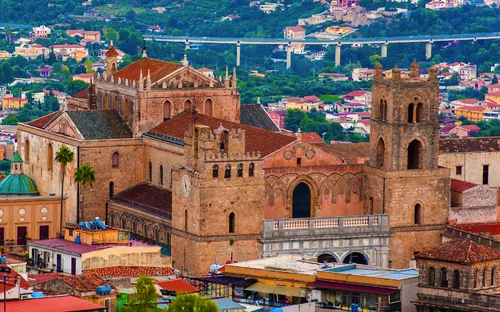 Historische Kathedrale in einer italienischen Stadtlandschaft mit Bergen im Hintergrund.