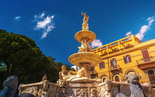 Marmorbrunnen des Orion in Messina, Sizilien vor einem Gebäude und blauem Himmel.