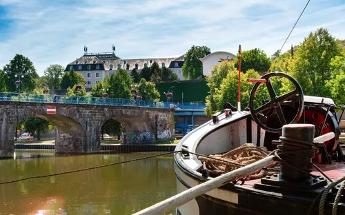 Blick auf eine Altstadtbrücke mit einem Boot im Vordergrund.