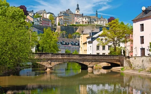 Blick auf Altstadt von Luxemburg mit Brücke über Fluss und historischen Gebäuden.
