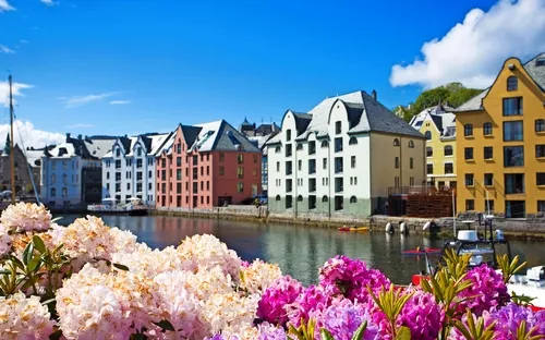 Bunte Häuser am Flussufer mit Blumen im Vordergrund.