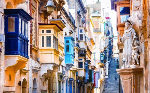 Bunte Balkone an einer engen, steilen Gasse in einer historischen Stadt.