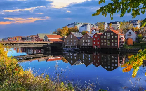 Bunte Häuser am Fluss mit Spiegelung im Wasser, Herbststimmung, blauer Himmel.