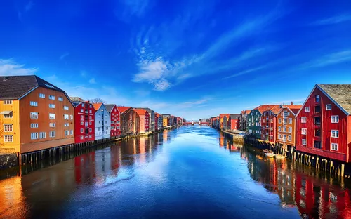 Bunte Häuser entlang des Trondheimer Fjords in Trondheim, Norwegen, unter klarem blauem Himmel.