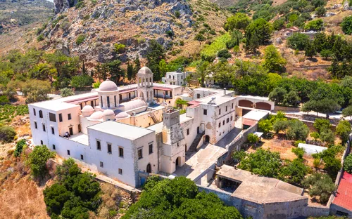 Klopra Monastery auf Kreta, umgeben von felsiger Landschaft und Bäumen.