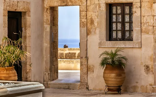 Innenhof mit Tontöpfen und Blick durch Tür auf das Meer