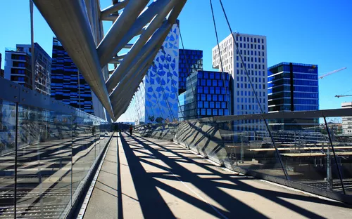 Moderne Fußgängerbrücke vor Bürogebäuden bei klarem Himmel.