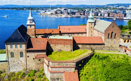Burganlage am Wasser mit Stadt im Hintergrund bei sonnigem Wetter