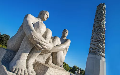 Skulpturen von zwei sitzenden Figuren vor einem Monolithen im Vigelandpark, Oslo.