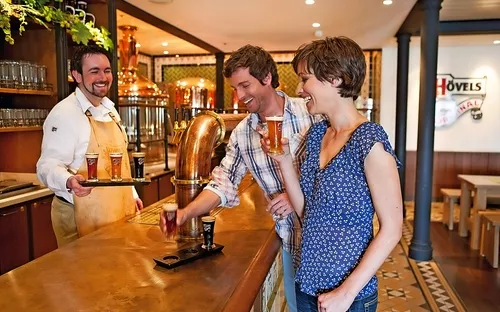 Personen genießen Getränke in einem Brauhaus mit einem Barkeeper.