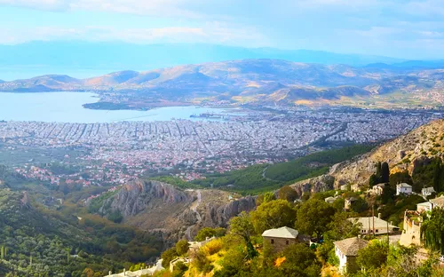 Panorama einer Küstenstadt mit Bergen im Hintergrund.