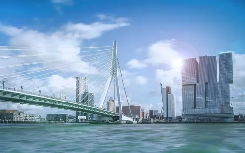 Stadtbild von Rotterdam mit Erasmusbrücke und modernen Gebäuden am Wasser.