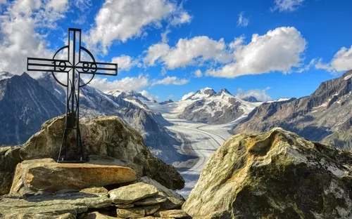 Kreuz auf Felsen vor Berglandschaft mit Gletscher im Hintergrund